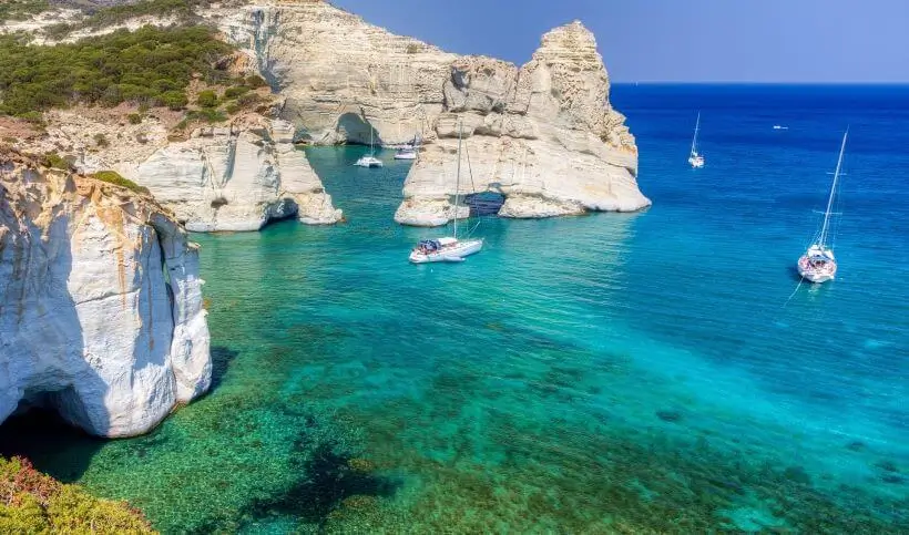 Thumbnail of Sailboats anchor in the clear turquoise water next to the striking white sea caves and rock arches of Kleftiko.